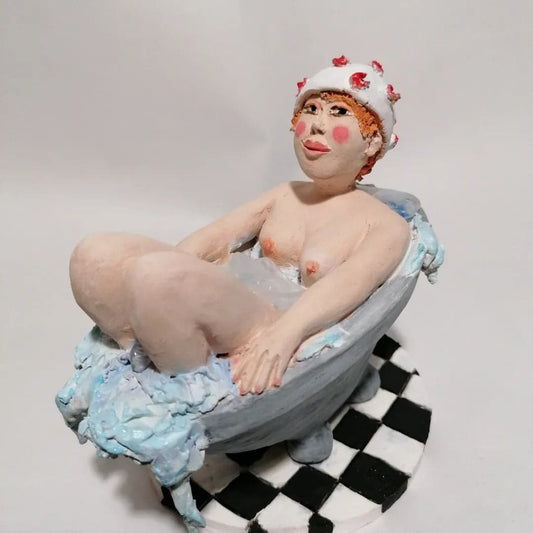 Sculpture artisanale colorée en grès avec couleurs en engobes  Baigneuse Rousse avec un bonnet de bain à fleurs dans une baignoire ancienne sur un carrelage en damier  Pièces unique 1/1  Dimension: 13x9,5x12,5 (Longueur x Largeur x Hauteur)  Poids: 0,600Kg  Made In France - Fabriqué en France  By Sandrine De Zorzi